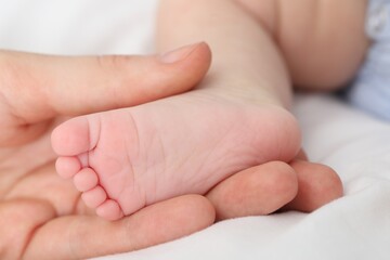 Mother with her little baby on bed indoors, closeup
