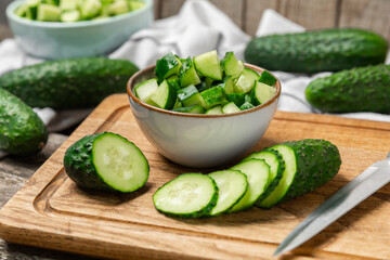 Cucumber on wooden background. Slice of cucumber on background. Fresh organic green cucumbers gherkin. Vegan. Salad ingredient. Farm vegetables. Cut vegetables with knife. Space for text. Copy space