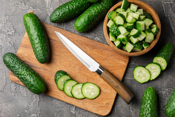 Cucumber on wooden background. Slice of cucumber on background. Fresh organic green cucumbers gherkin. Vegan. Salad ingredient. Farm vegetables. Cut vegetables with knife. Space for text. Copy space