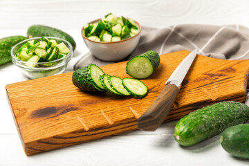 Cucumber on wooden background. Slice of cucumber on background. Fresh organic green cucumbers gherkin. Vegan. Salad ingredient. Farm vegetables. Cut vegetables with knife. Space for text. Copy space
