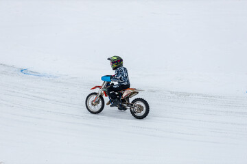 A man is riding a dirt bike on a snowy road