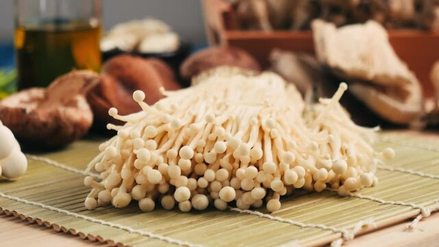 Fresh golden needle mushroom or enoki, enokitake (Flammulina velutipes) on wooden plate, close up macro of vegan food.