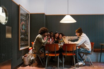 A group of five friends sitting at a table and smiling while talking