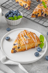 Blueberry scones with lemon glaze on top on a gray concrete background. Delicious breakfast.