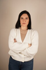 Studio portrait of attractive dark-haired smiling woman with arms crossed in front of chest. Isolated background. Vertical photo.