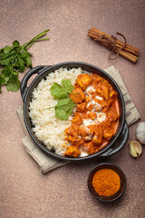 Aromatic Indian chicken tikka masala served with rice and coriander, turmeric, garlic, cinnamon sticks, traditional dish of India top view