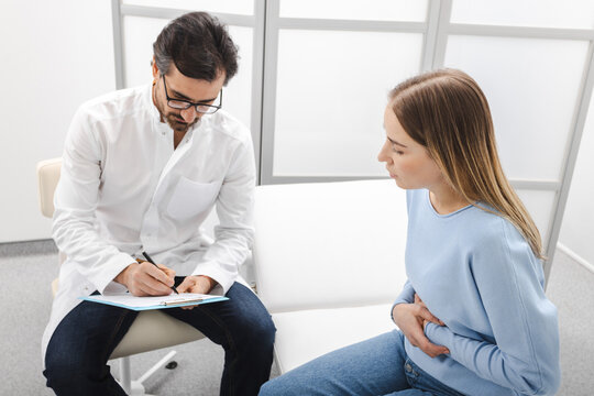 Doctor prescribes treatment for female patient with abdominal pain. Gastroenterology
