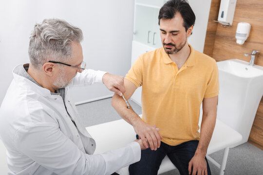 Neurology. Checking man hand reflexes using neurological needle wheel in a neurological clinic, close-up