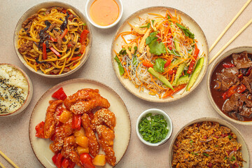 Assorted Chinese dishes, sweet and sour chicken, beef in sauce, noodles, fried rice, salad and wooden chopsticks. Chinese or Asian restaurant concept