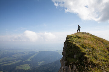 Man stands on a rocky outcrop while hiking up Mount Pilatus and gazes into the distance.