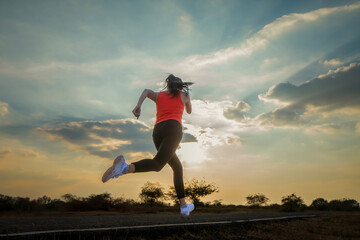 Silhouette of a beautiful young woman running against a colorful sky. Silhouette of a beautiful young woman running against a sunset background.