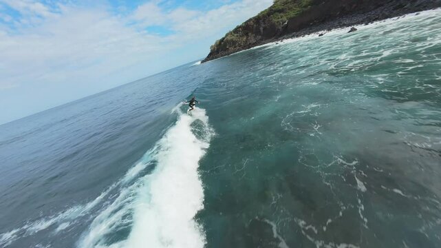 Professional surfer skillfully rides powerful ocean waves at Playa Nogales, capturing dynamic surfing action against scenic La Palma coastline under bright blue sky