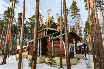 A small wooden church with golden domes and a cross on top of it in Yekaterenburg Russia