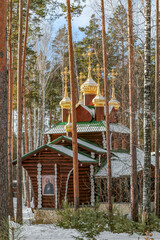 A small wooden church with golden domes and a cross on top of it in Yekaterenburg Russia