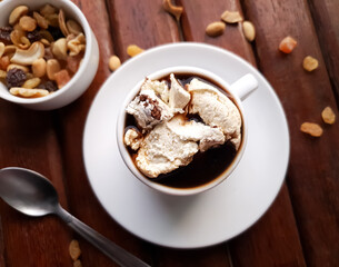 coffee with cream and chocolate cookies in white cup on wooden background