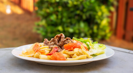 Beef stir fried with macaroni, Vietnamese cuisine, nui xao bo. Beef is fermented with salt, black pepper, stir fried separately. Onions, tomatoes, boiled macaroni adds in the mixture with medium fire