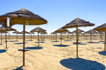 spiaggia con ombrelloni di paglia e sabbia, beach with straw umbrellas and sand