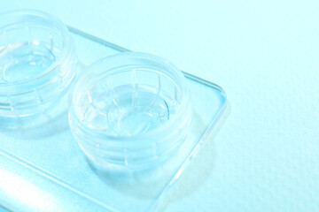Case with contact lenses on light blue background, closeup
