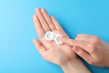 Woman with contact lenses on light blue background, closeup