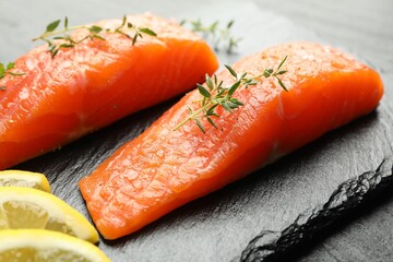 Seafood. Pieces of salmon fillet, thyme and lemon slices on table, closeup