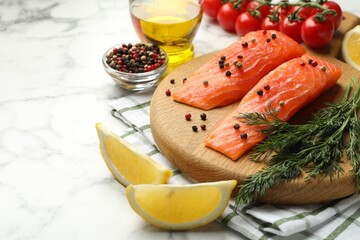 Seafood. Pieces of salmon fillet, tomatoes, oil, spices and lemon wedges on white marble table,...