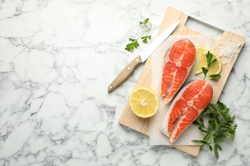 Seafood. Fresh raw salmon steaks, parsley, pieces of lemon and salt on white marble table, top view. Space for text