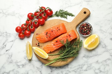 Seafood. Pieces of salmon fillet, spices, tomatoes and lemon wedges on white marble table, flat lay
