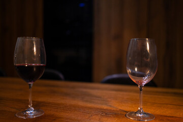 Stream of Red Wine Pouring into Empty Wine Glass on Wooden Table