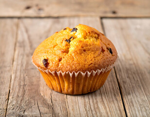 A delicious chocolate muffin, a sweet baked pastry, rests on a brown wooden table