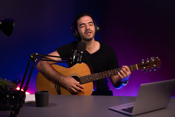 Obraz premium Host channel of smart influencer in creative audio on live streaming to fanclub with sing with play guitar music blogger using headset and mic social media online at neon light modern studio. Surmise.