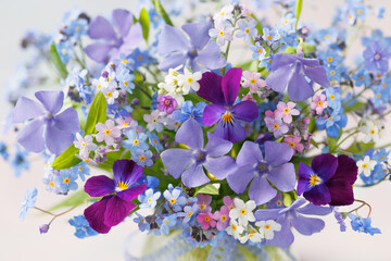 Bouquet of spring flowers forget-me-nots, pansies violets, periwinkle close-up in a vase, blur, beautiful card