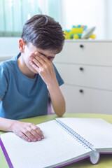 Visually impaired boy feeling tired while reading Braille book. Child with visual impairment rubbing eyes. Special Education and Inclusive Learning. 