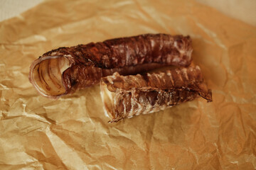 Natural dog treats dried beef trachea close-up on brown craft paper. Healthy chew snack for pets, rich in chondroitin and glucosamine.