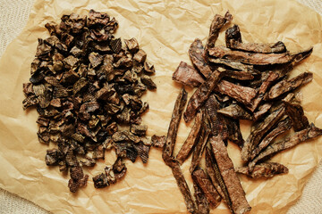 Close-up of natural dried beef lung dog treats in small chunks and long strips, displayed on brown craft paper. Healthy, single-ingredient pet snacks for dogs, ideal for training or rewarding.
