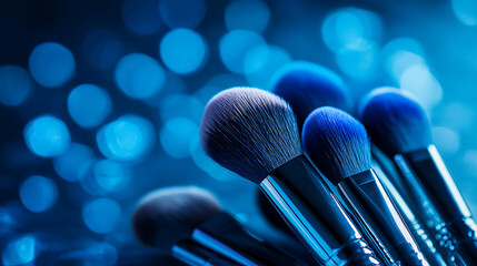 Professional makeup brushes arranged artistically against vibrant blue background, creating visually striking effect. soft bristles and shiny handles reflect light beautifully, evoking sense