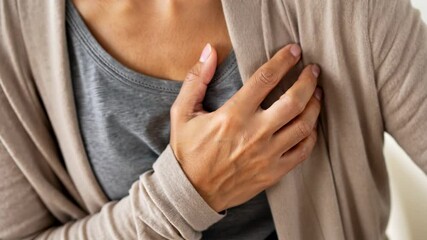 Person holding chest with hand, experiencing heart discomfort.