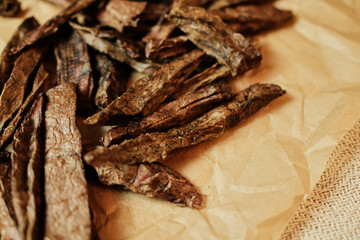 Macro shot of dried beef lung dog treats in long strip form, arranged on kraft paper. Natural high-protein snacks for dogs suitable for training or daily rewarding. Healthy single-ingredient pet food.