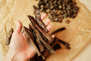 Hand holding long strips of dried beef lung dog treats. Natural grain-free and high-protein snack...