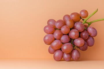 Bunch of fresh red grapes on a soft peach background showing natural colors and textures in a simple arrangement