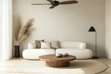 A minimalist, beige living room with a comfortable, rounded sofa, a wooden coffee table, and a neutral color scheme.  A ceiling fan, pampas grass, and a floor lamp add to the warm and airy atmosphere