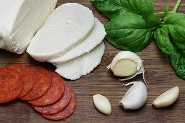 Italian ingredients on cutting board , Basil, Pepperoni, Garlic, Mozzarella