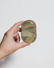 Hand holding a military camouflage patch symbolizing service and sacrifice for Veterans Day (USA) and copy space