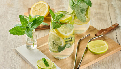 Refreshing citrus and mint drink in glasses with ice, lemon, lime, and mint leaves. Healthy summer...