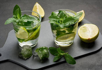 Refreshing mojito cocktail with lime, mint, and ice on dark background
