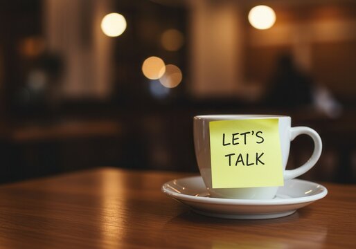 Coffee cup with let's talk note on a wooden table in a cafe setting