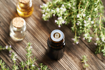 A dark bottle of thyme essential oil on a wooden background