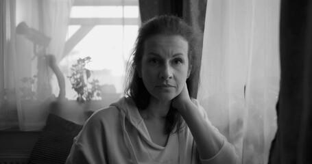 Black and white portrait of a woman resting her head on her hand, looking directly at the camera...