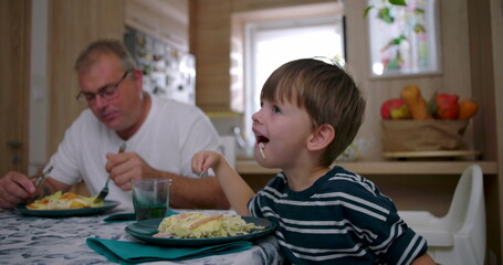 Father and son eating together at the table during a family meal, showcasing authentic connection and everyday family life in a cozy home setting