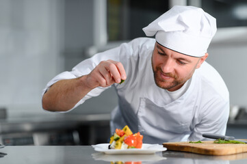 food cooking, profession and people concept - happy male chef cook with plate of salad at restaurant kitchen table