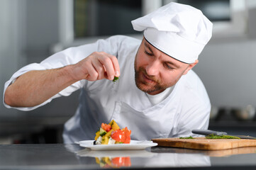 food cooking, profession and people concept - happy male chef cook with plate of salad at restaurant kitchen table